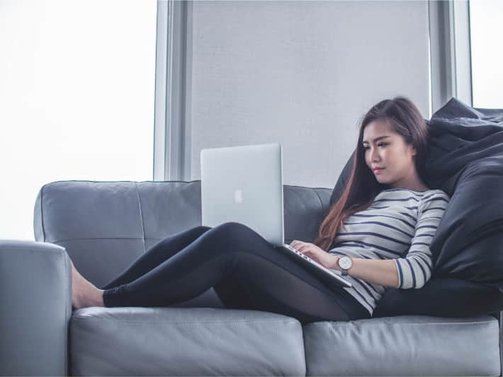 Vrouw die een laptop gebruikt op de bank