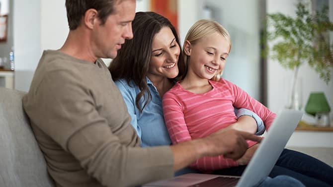 Met een privéblog kun je vermijden dat vreemden persoonlijke details over je gezin te weten komen. Afbeelding van twee ouders en hun dochter op een bank die samen naar een tablet kijken.